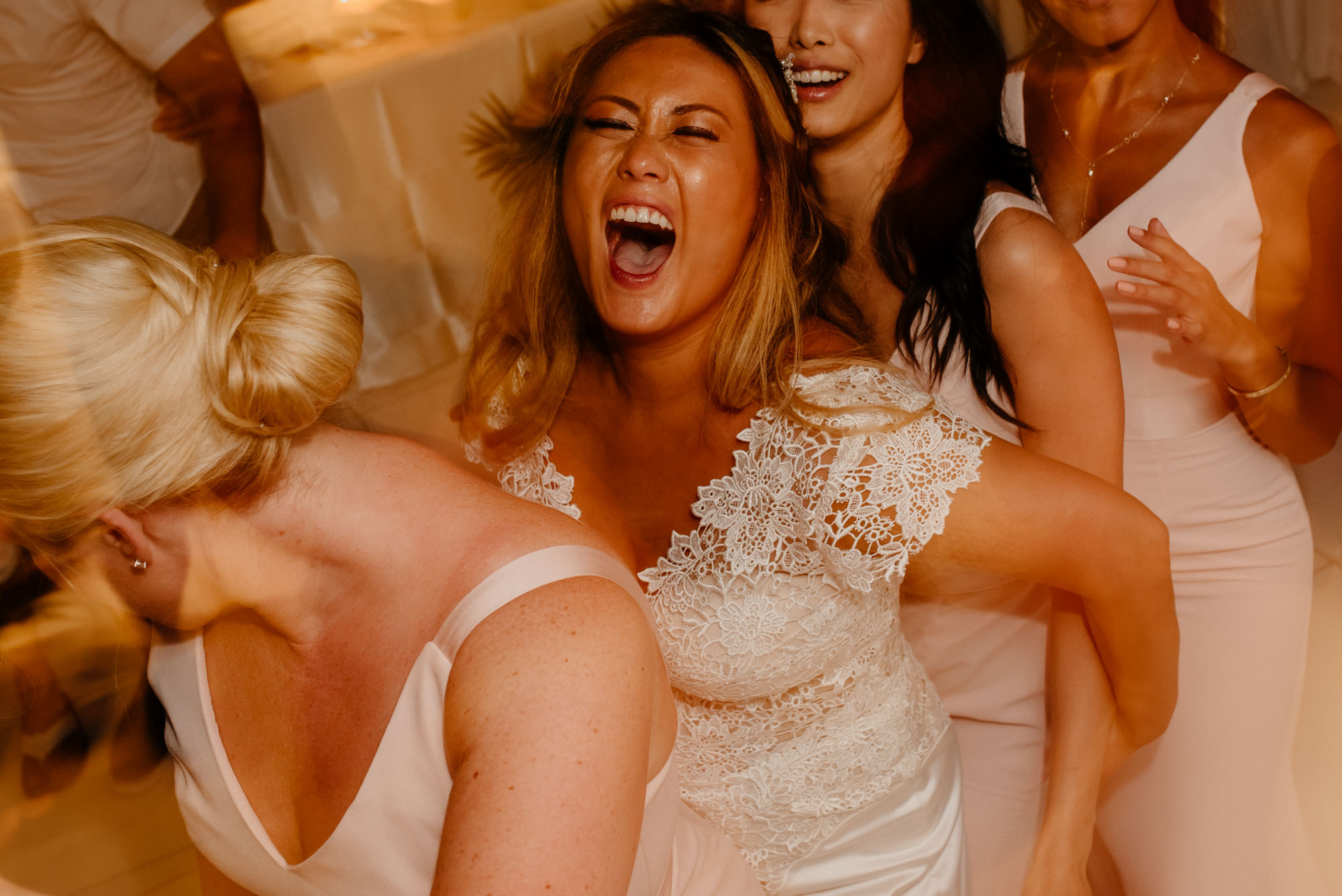 the bride is laughing when dancing with the bridal party