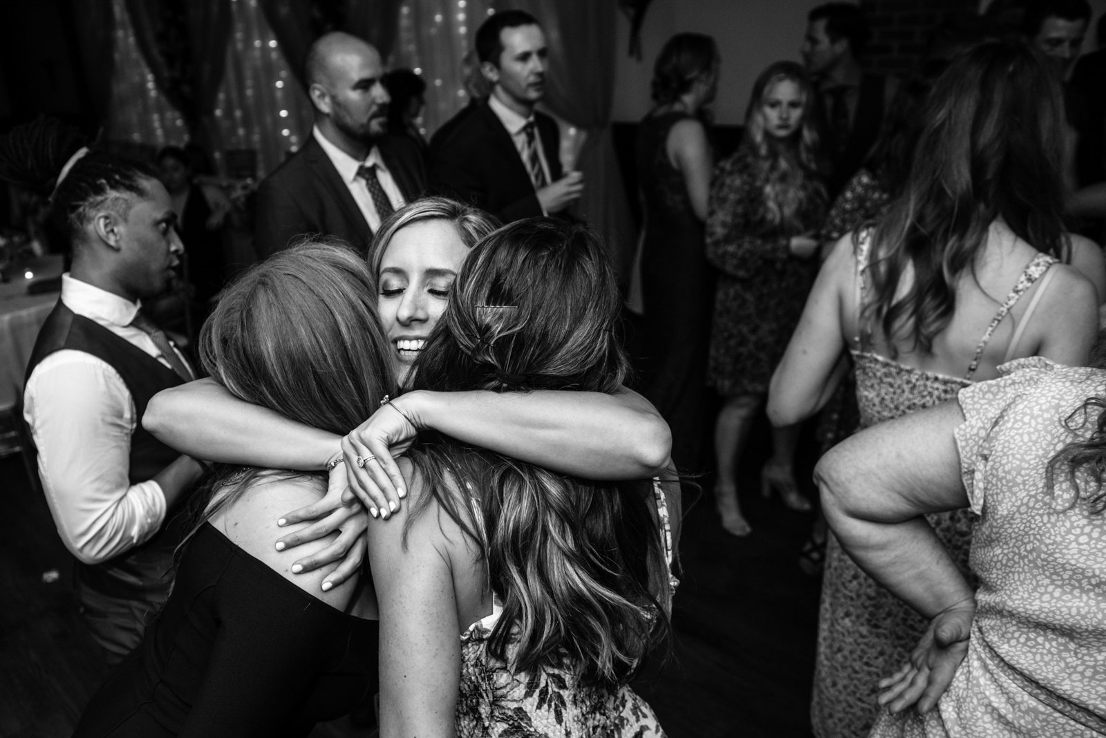 the bride is tightly hugging her friends