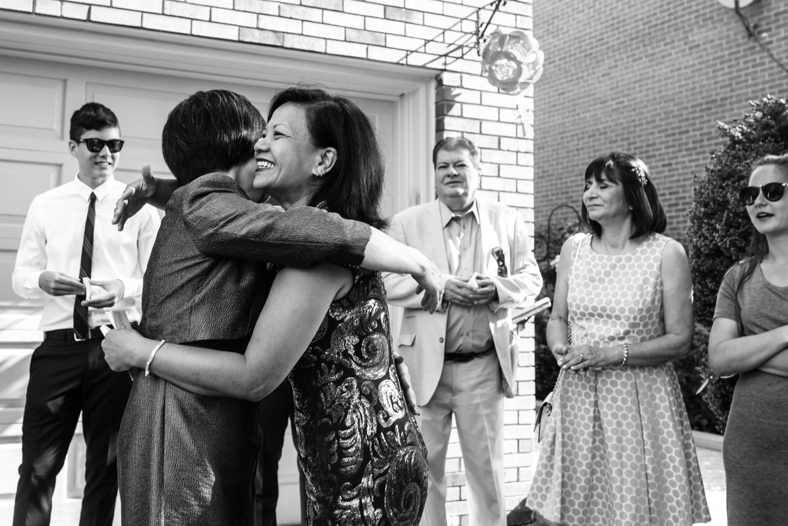 candid shot of the bride's mom hug guest in front of her house on the wedding day morning taken by documentary wedding photographer cafa liu